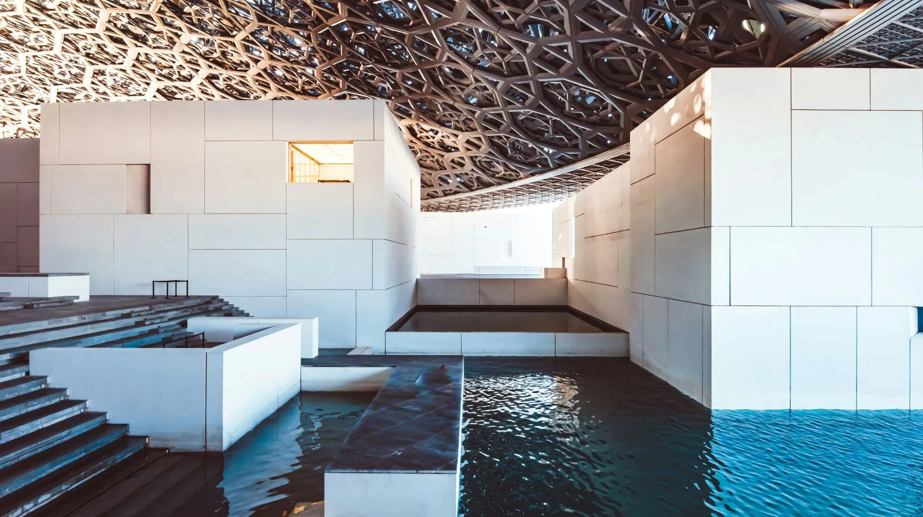 Architecture moderne et épurée du louvre à Abu dhabi avec des jeux d'eau, ambiance paisible et lumineuse.