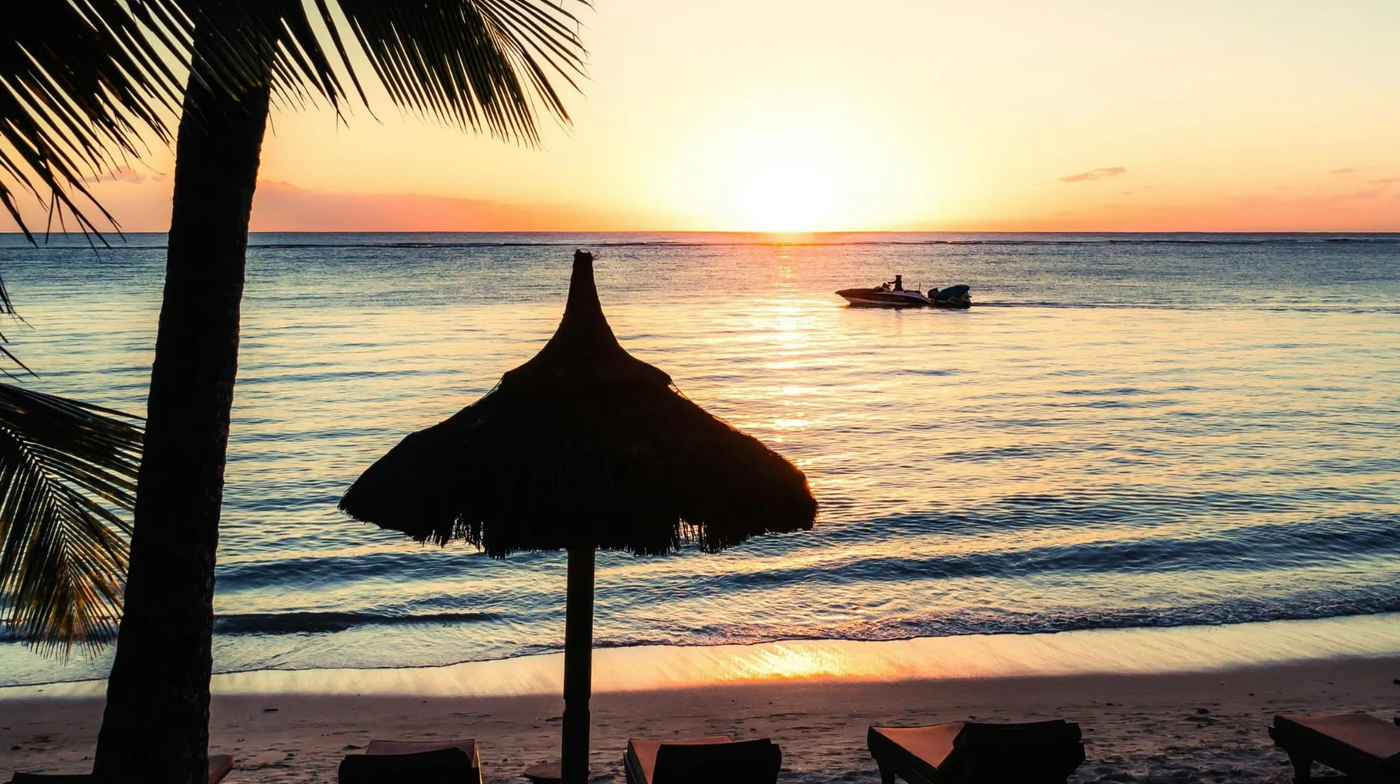 Coucher de soleil sur la plage des Maldives avec bateau et parasol en bord de mer
