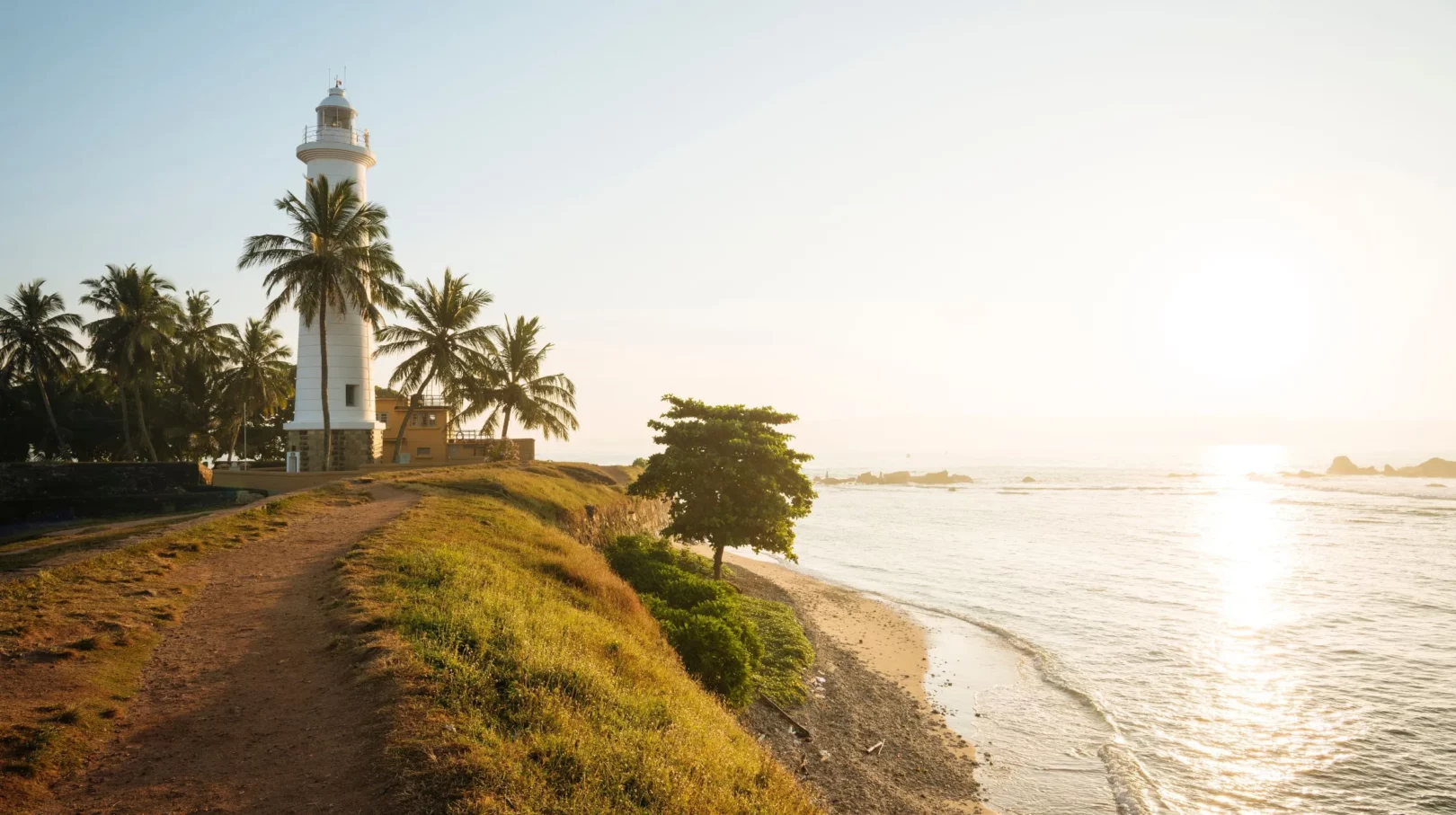 Phare majestueux de Galle au Sri Lanka au bord de l'océan, entouré de palmiers, offrant une vue spectaculaire au coucher du soleil.