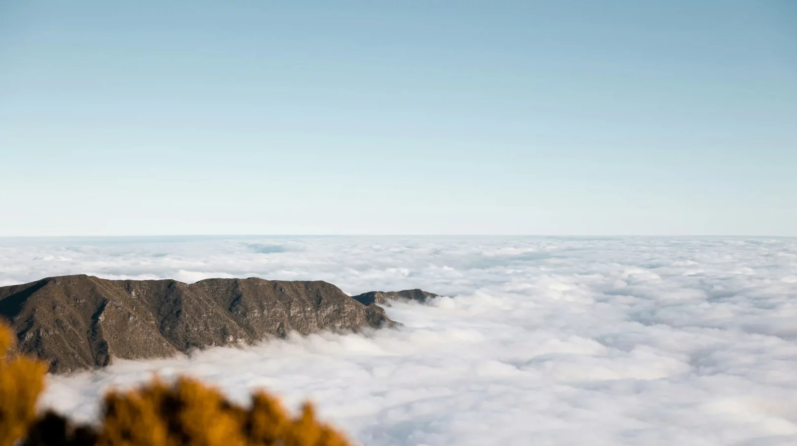 Vue spectaculaire sur des montagnes de la Réunion émergeant d'une mer de nuages, offrant un paysage époustouflant et serein.