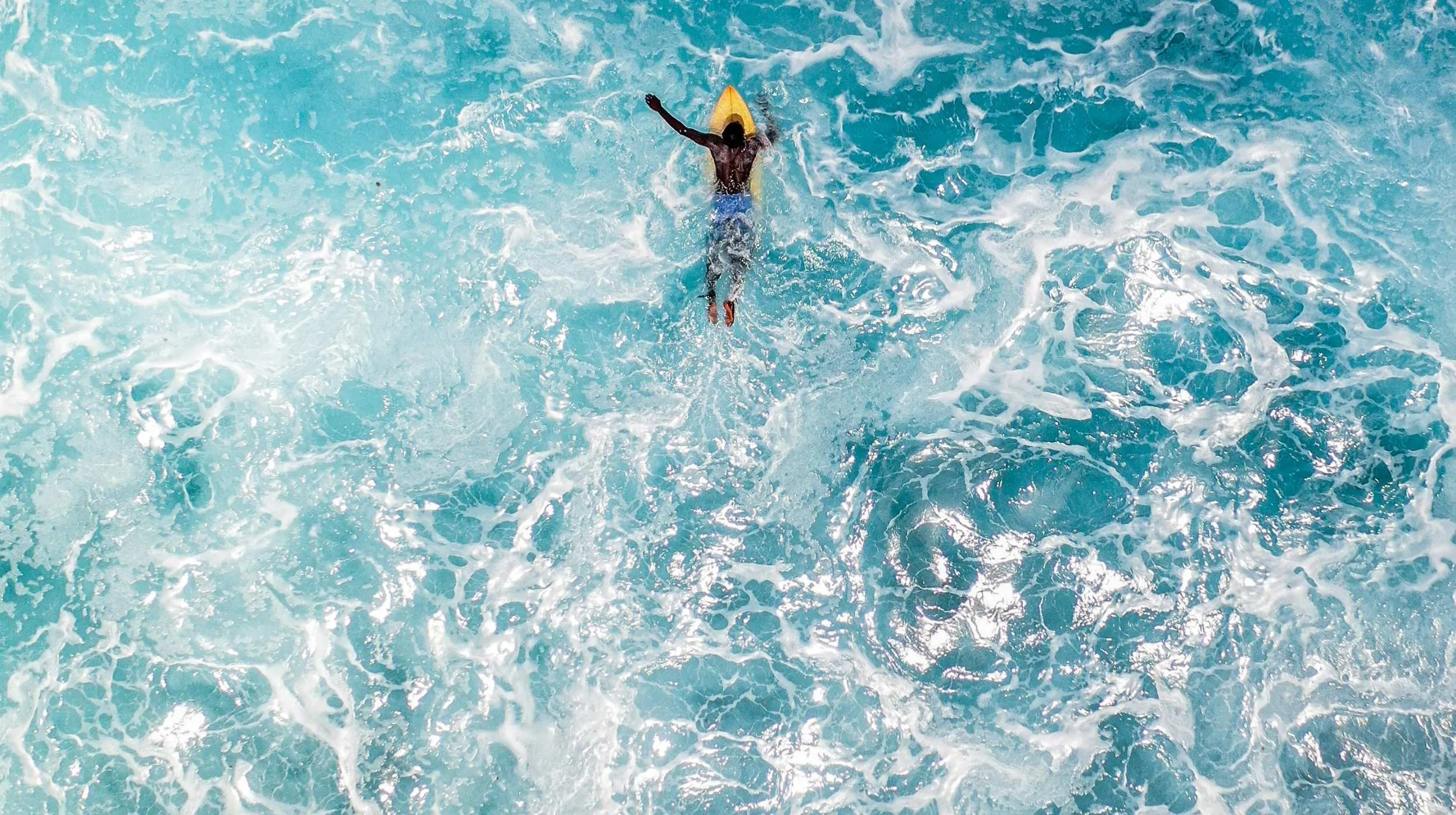 Surfeur sur une vague turquoise aux Maldives