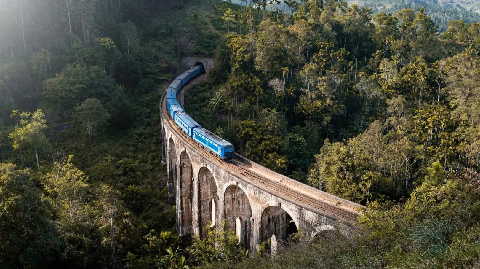 Train bleu traversant le pont aux neuf arches dans la jungle luxuriante d’Ella, Sri Lanka, voyage panoramique emblématique et attraction touristique incontournable
