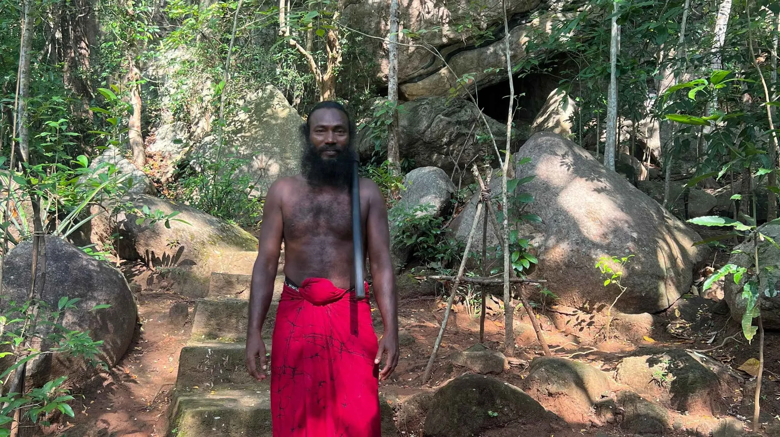 veddah dans la foret devant des escaliers