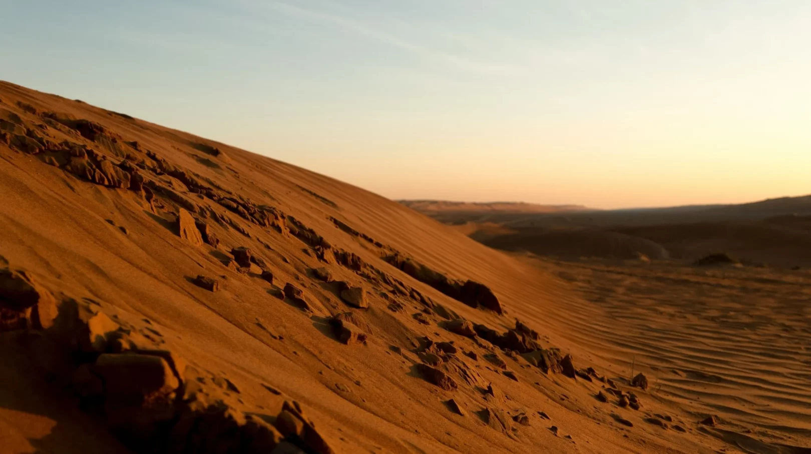 Coucher de soleil sur les dunes rouges de Wahiba Sands, désert emblématique d’Oman, dans le cadre du circuit Oman Émotions.