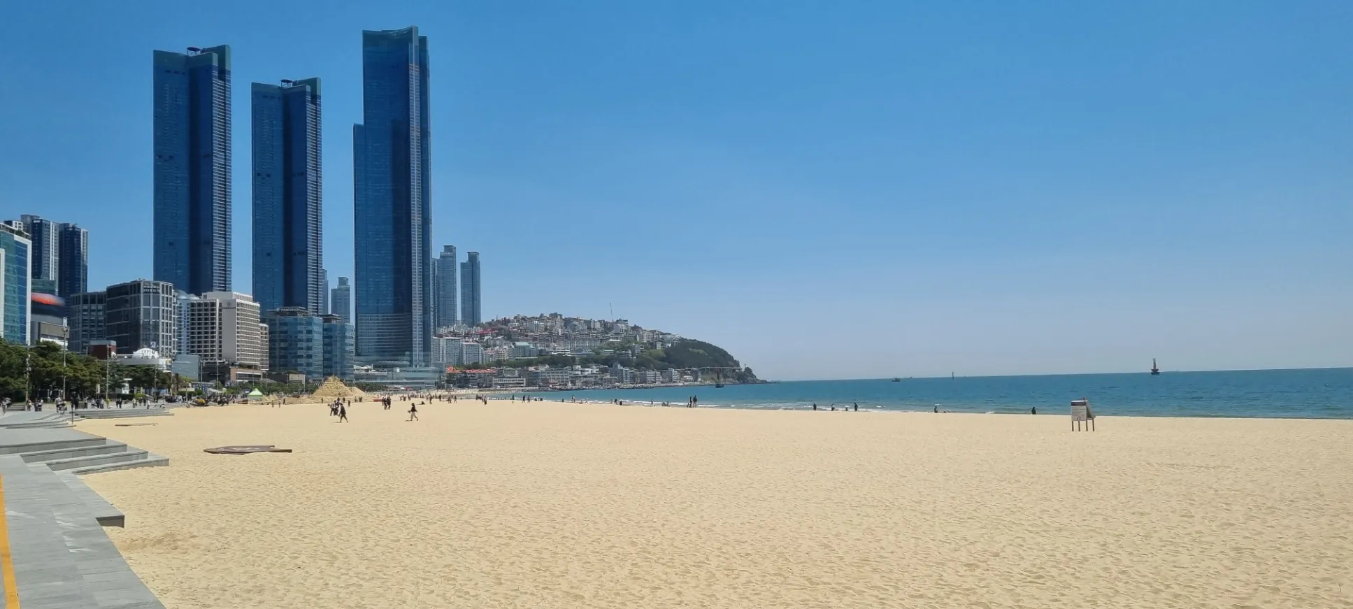 Plage animée avec des gratte-ciels en arrière-plan, Corée du Sud — paysage ensoleillé et moderne.