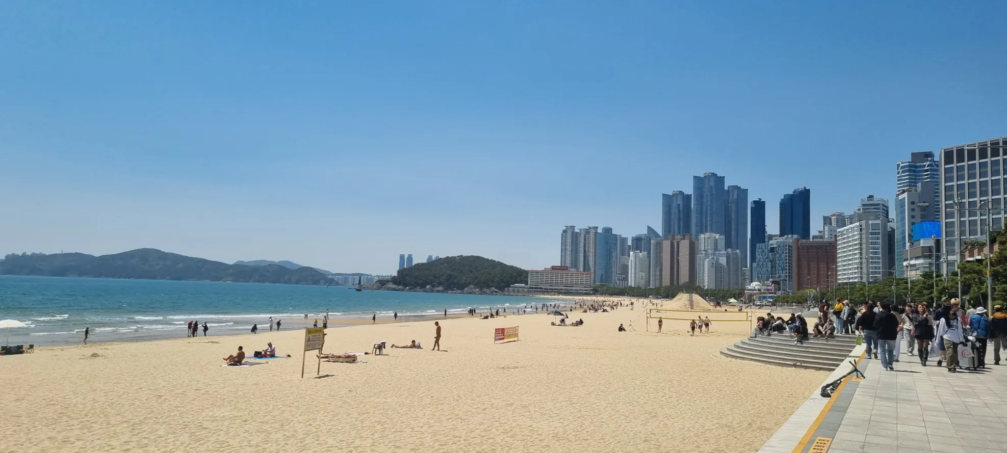 Plage animée avec gratte-ciels en arrière-plan, Corée du Sud — ambiance estivale et conviviale.