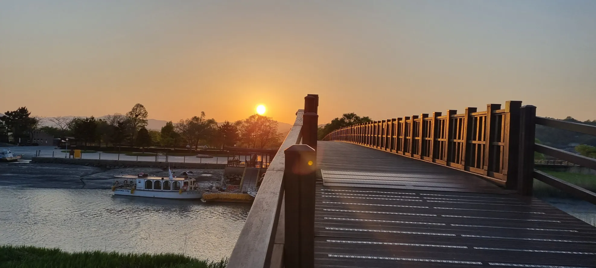 Coucher de soleil enchanteur sur un pont au bord de l'eau, créant une ambiance paisible.