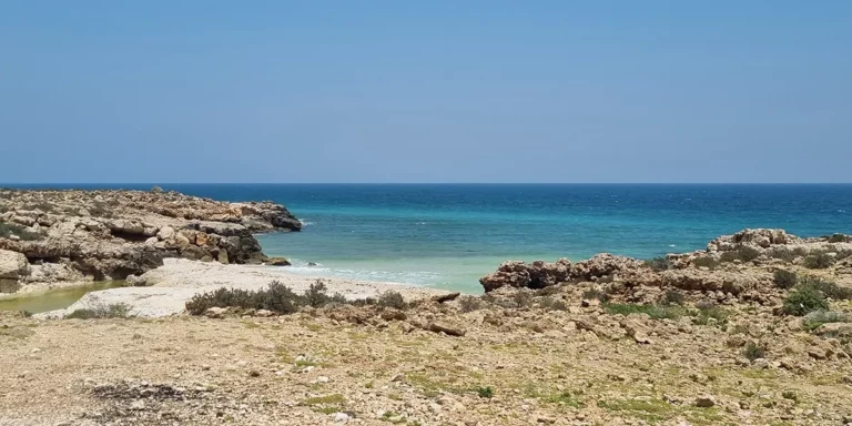 Plage sauvage et paisible, aux eaux turquoise, entourée de rochers, idéale pour une escapade relaxante.