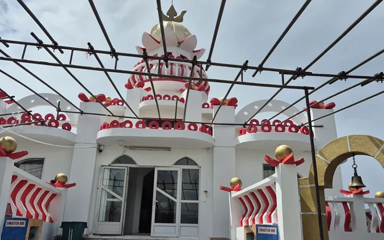 Édifice coloré avec des motifs décoratifs, ambiance accueillante et charmante, sous un ciel nuageux.