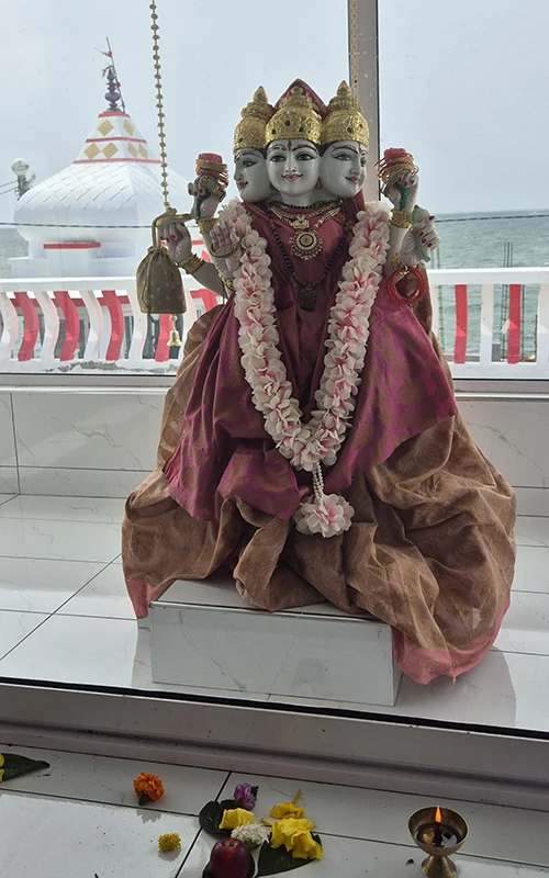 Statue colorée de divinité dans un temple, ambiance paisible et spirituelle, décorée de fleurs.