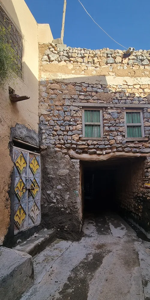 Ruelle pittoresque avec des murs en pierre et une porte colorée, évoquant un charme authentique.