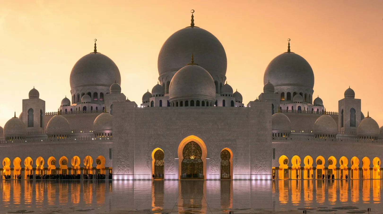 Abu Dhabi, Émirats Arabes Unis — majestueuse mosquée illuminée au crépuscule, reflet sur l'eau.
