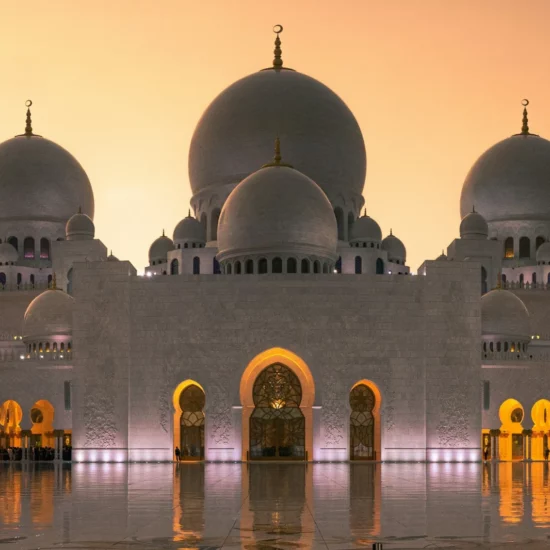 Abu Dhabi, Émirats Arabes Unis — majestueuse mosquée illuminée au crépuscule, reflet sur l'eau.