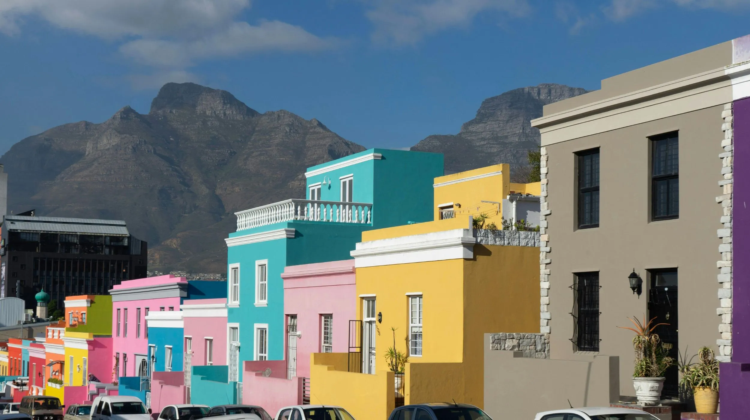 Maisons colorées dans un quartier animé — Afrique du Sud, avec des montagnes majestueuses en arrière-plan.