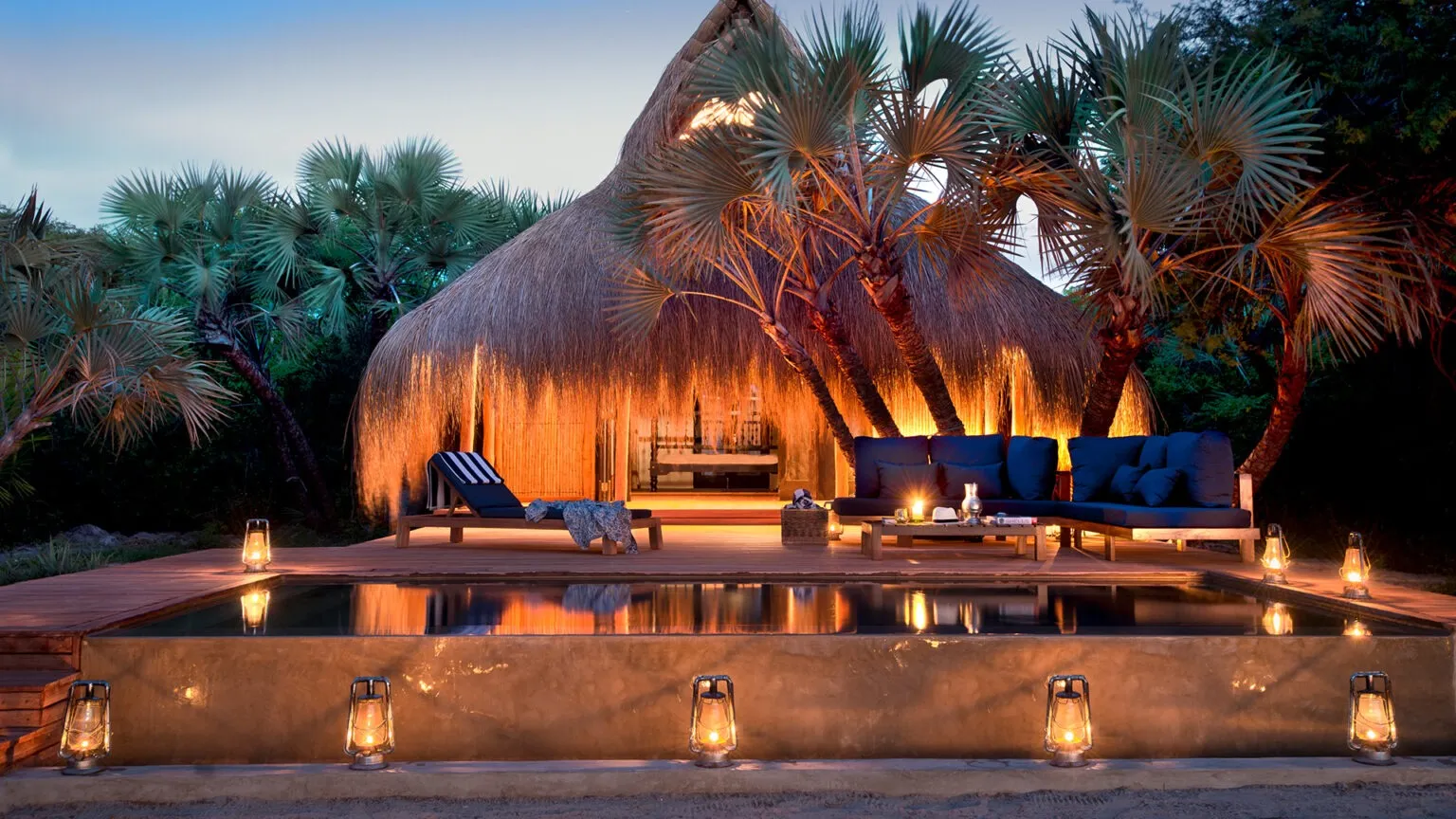 Un cadre enchanteur avec une piscine paisible, entouré de palmiers et d'une cabane en toit de chaume.