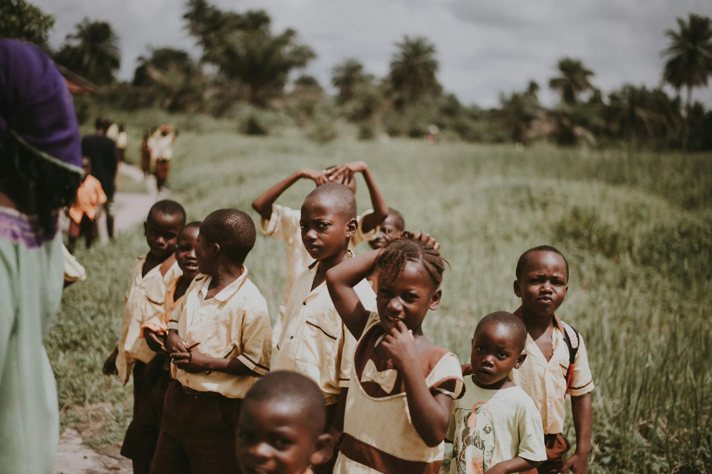 Groupe d'enfants souriants dans un paysage verdoyant et ensoleillé, ambiance conviviale et joyeuse.