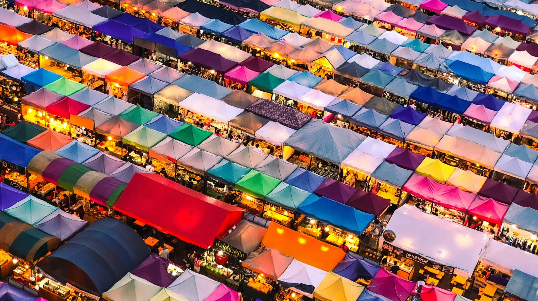 Marché vibrant avec des tentes colorées, ambiance animée et conviviale, typique d’Asie.