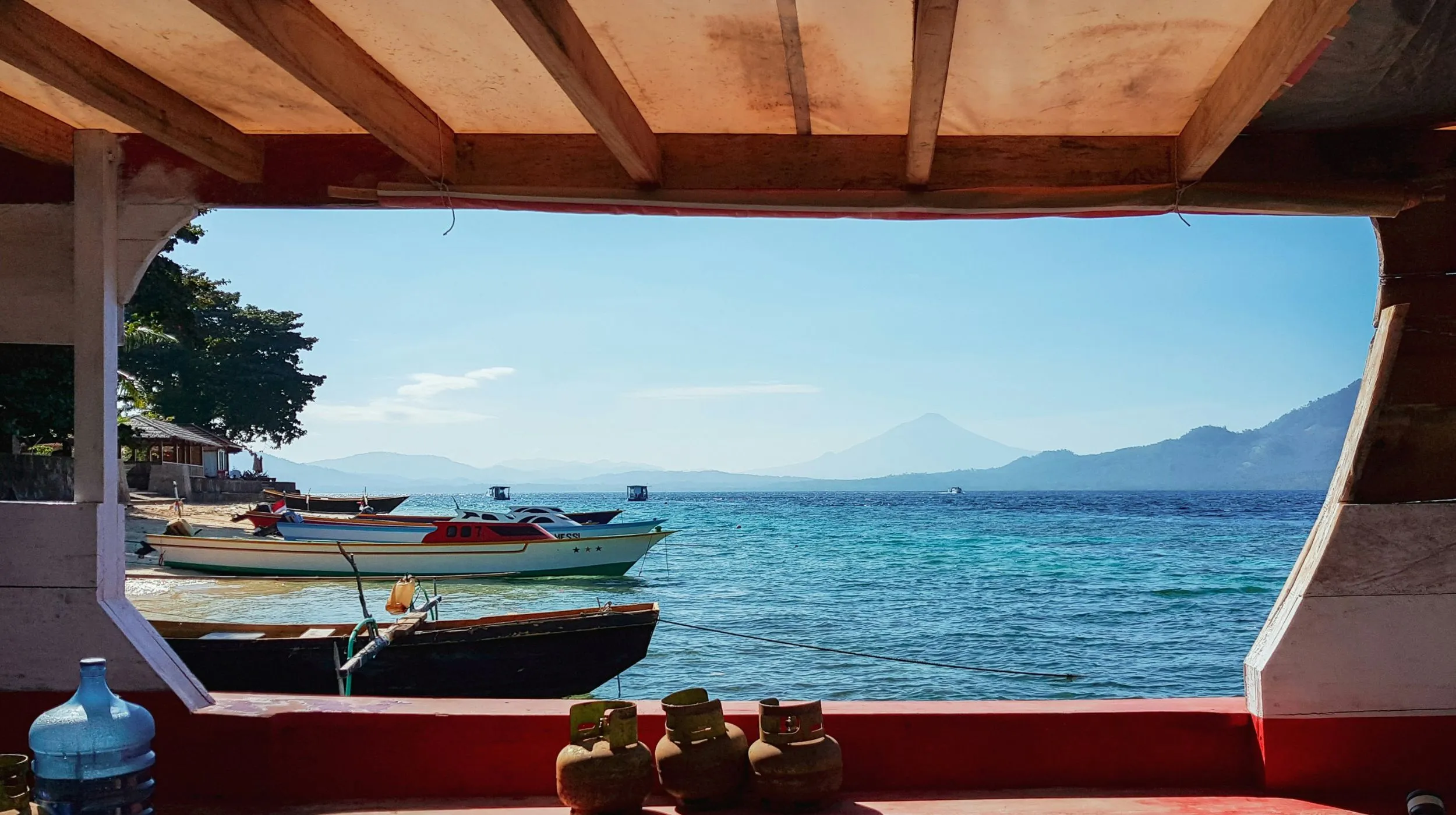 Vue paisible sur la mer avec des bateaux colorés et des montagnes en arrière-plan, ambiance tropicale.