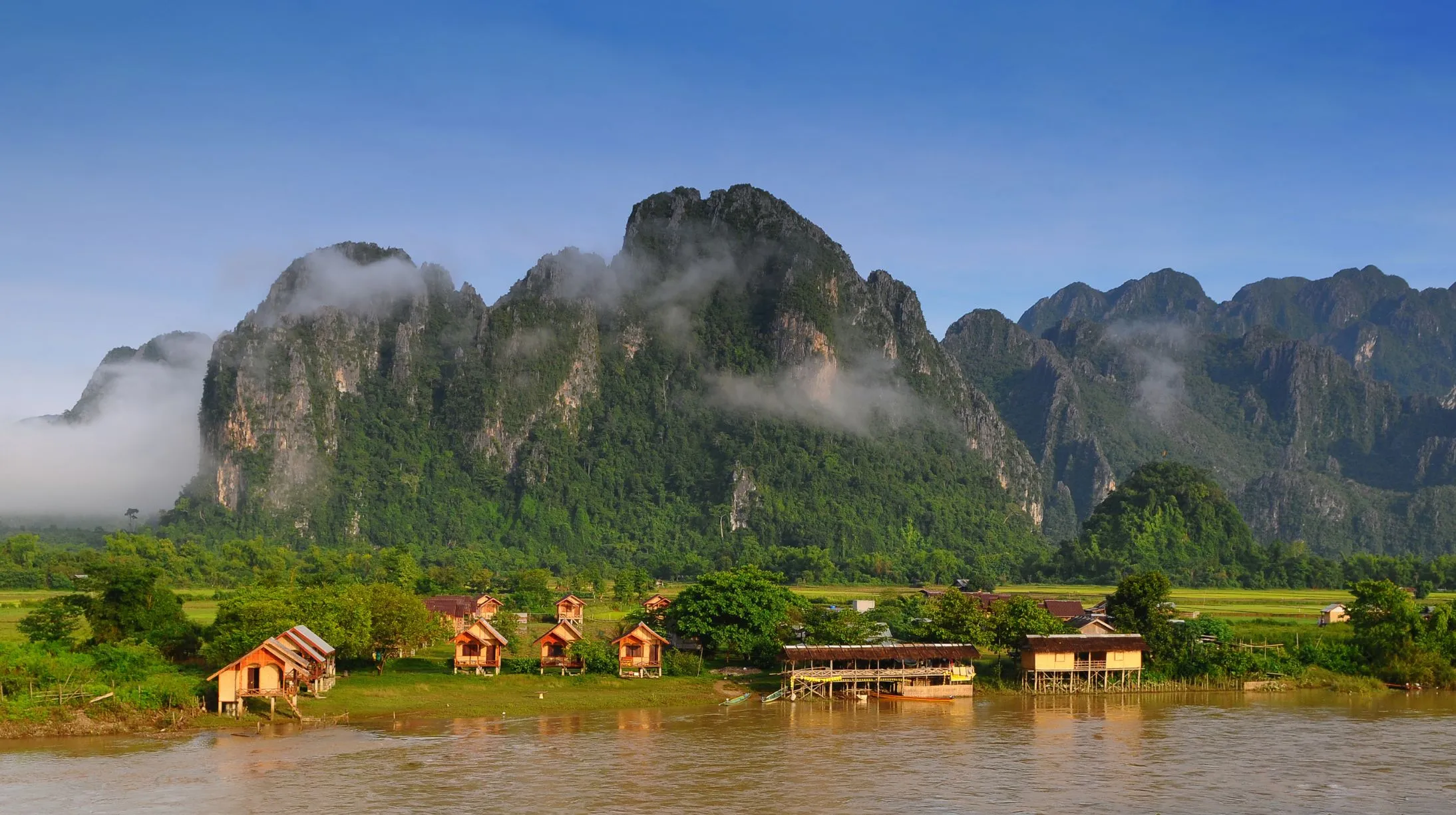Paysages pittoresques avec montagnes majestueuses et maisons au bord de l'eau, Laos.