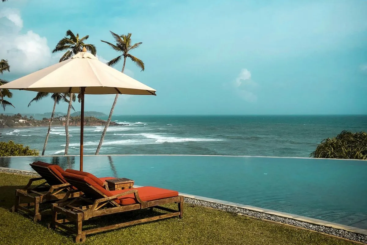 Vue spectaculaire sur l'océan depuis une piscine à débordement, entourée de palmiers luxuriants.
