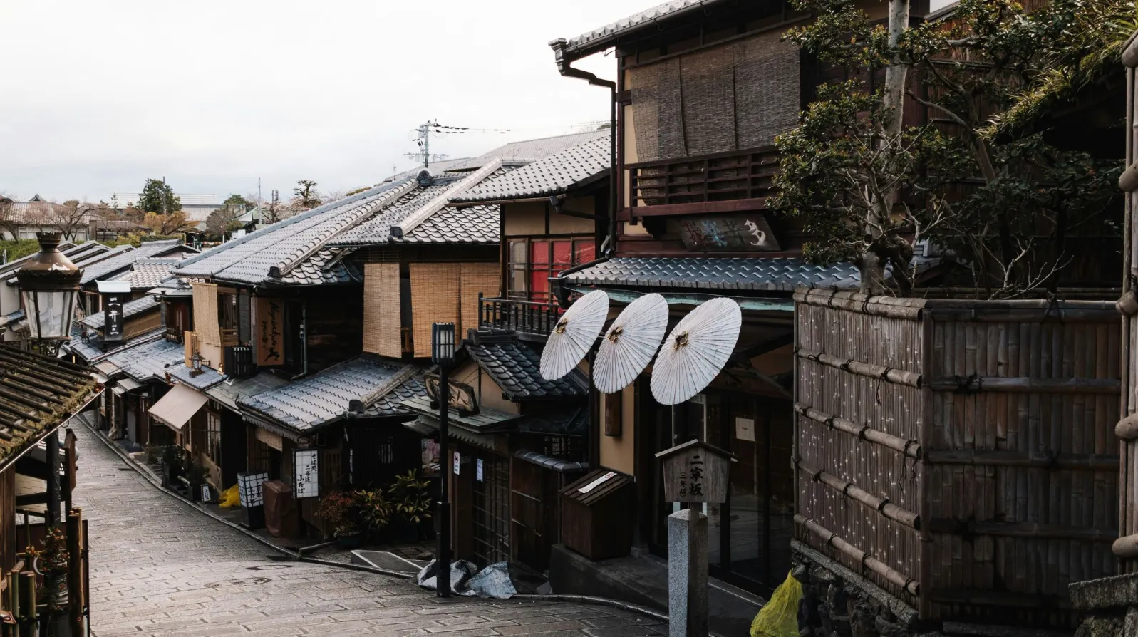 Kyoto, Japon — ruelle pittoresque bordée de maisons traditionnelles et de parasols en papier.