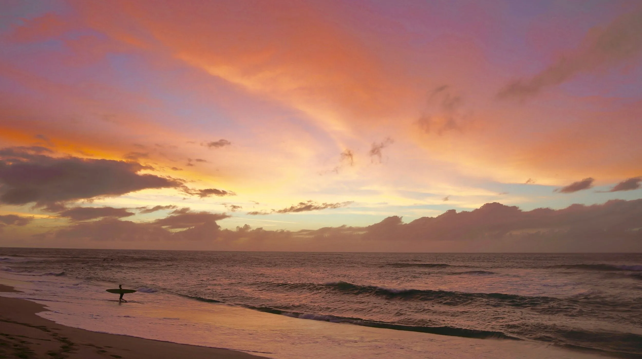 Coucher de soleil spectaculaire sur une plage paisible, reflet des couleurs chaudes sur l'eau.