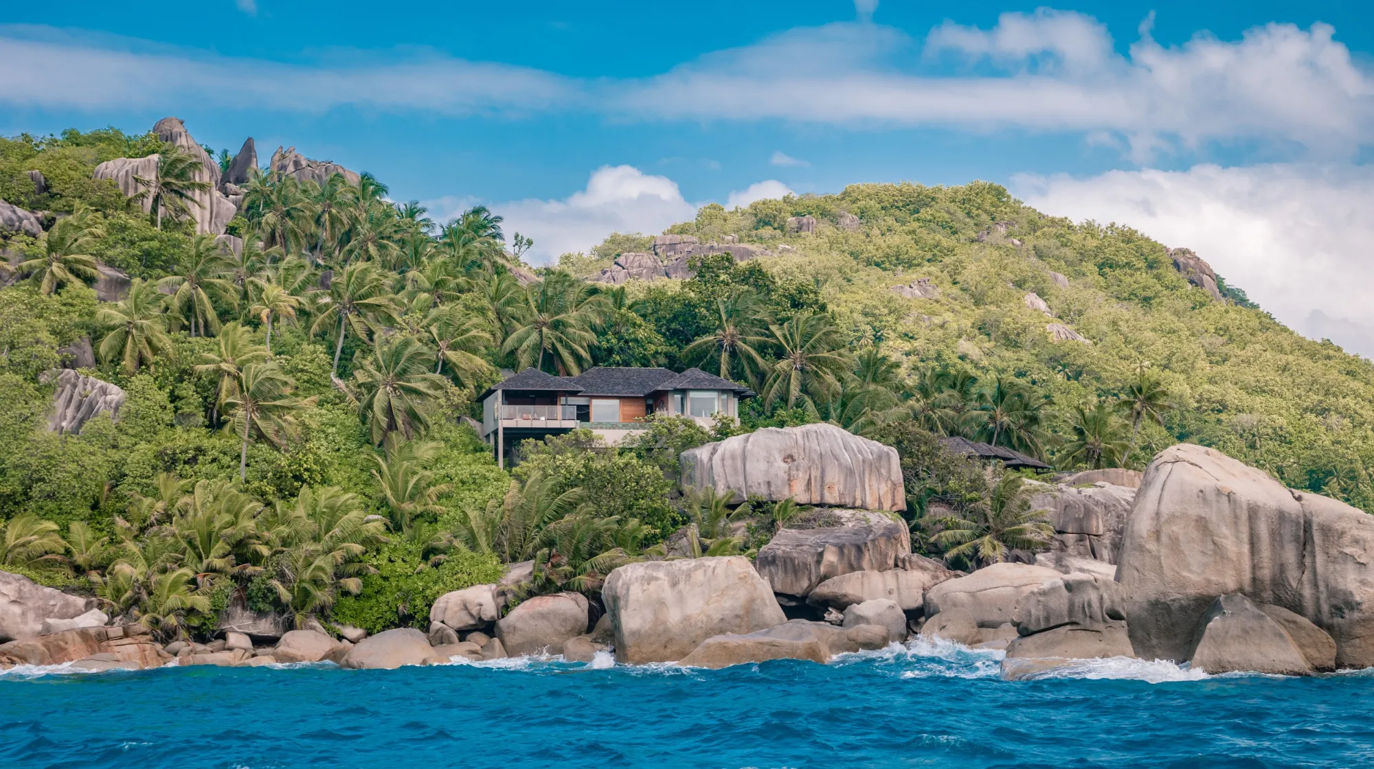 Côte sauvage et luxuriante, avec des rochers et des palmiers, évoquant un paradis tropical.