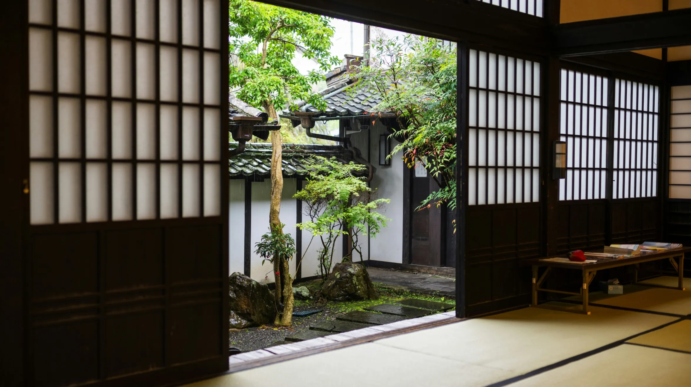 Japon — Intérieur d'une maison traditionnelle avec un jardin paisible et verdoyant visible à travers une porte coulissante.