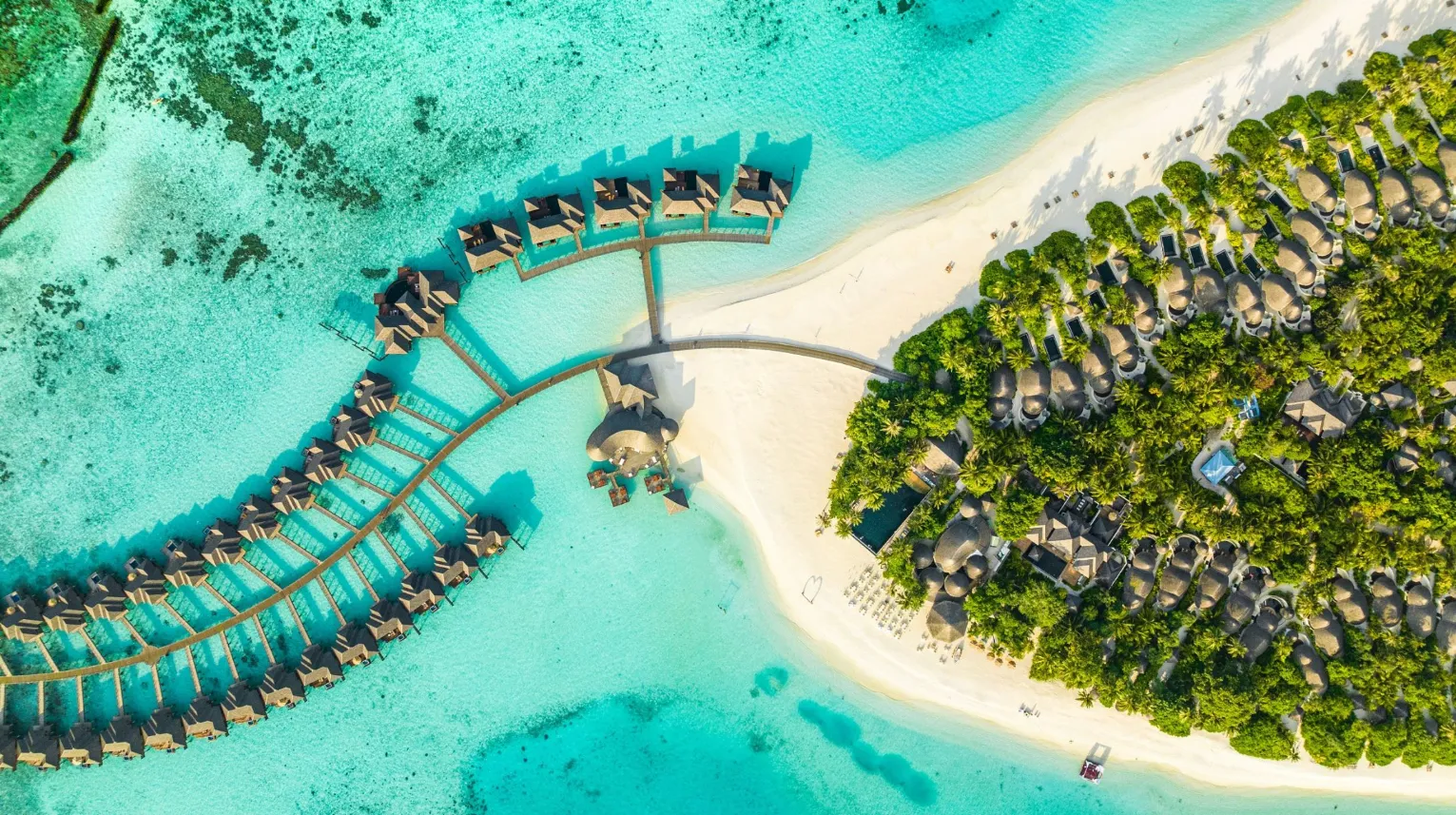 Île paradisiaque, Maldives — vue aérienne sur des bungalows en bois entourés d'eaux turquoise et de plages de sable blanc.