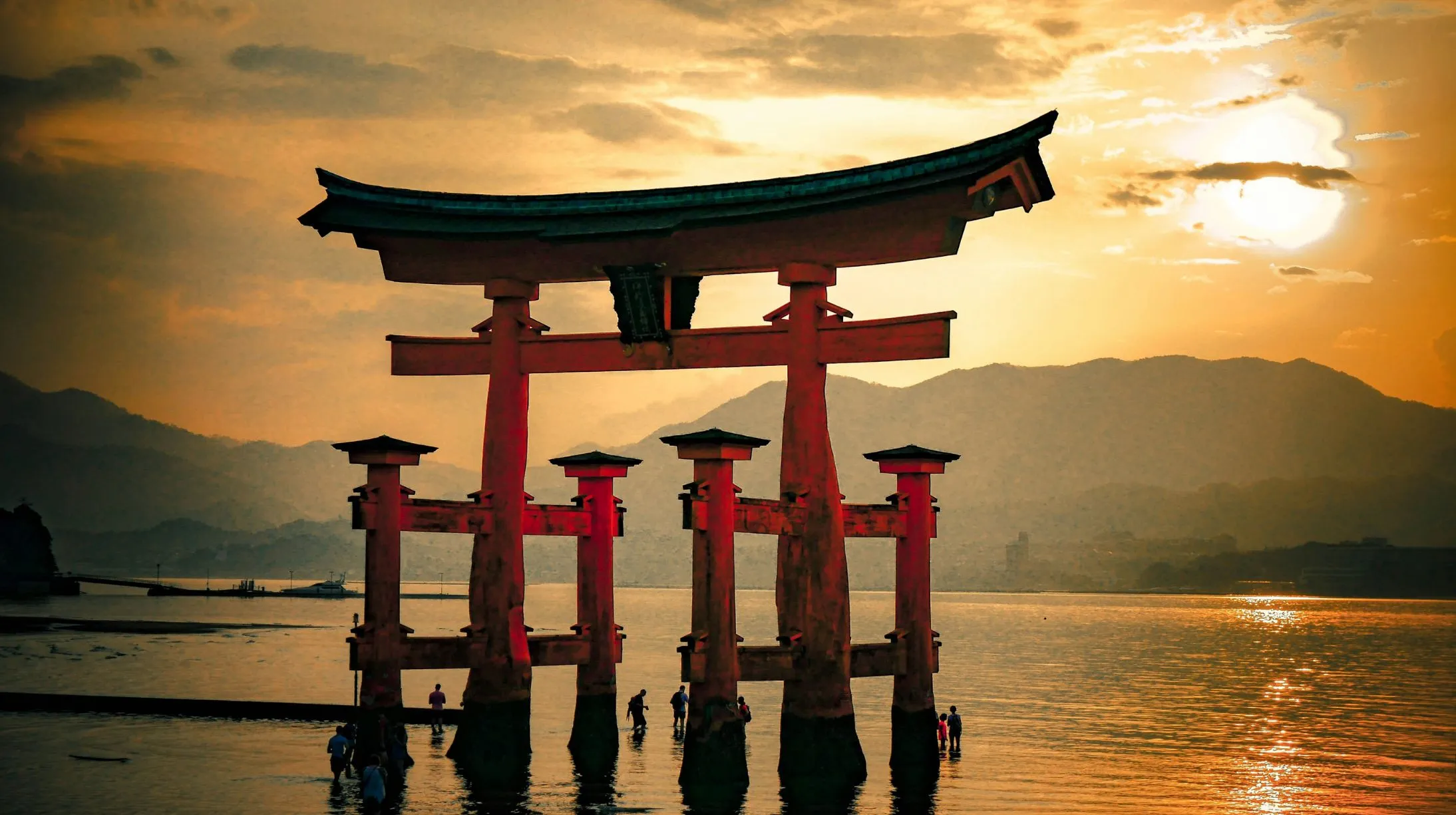 Torii, Japon — silhouette majestueuse au coucher du soleil, reflet sur l'eau apaisante.