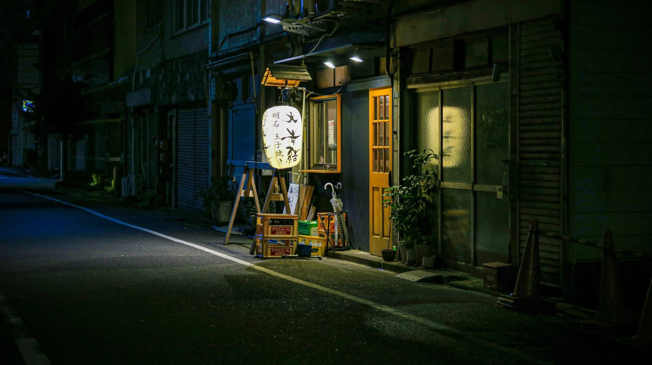 Ruelle tranquille, Japon — ambiance nocturne avec un lanternon illuminé et des éléments architecturaux charmants.