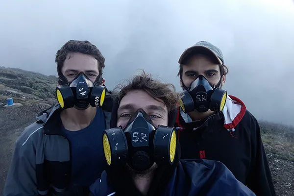 Trois aventuriers masqués se préparent à explorer un paysage mystérieux et brumeux.