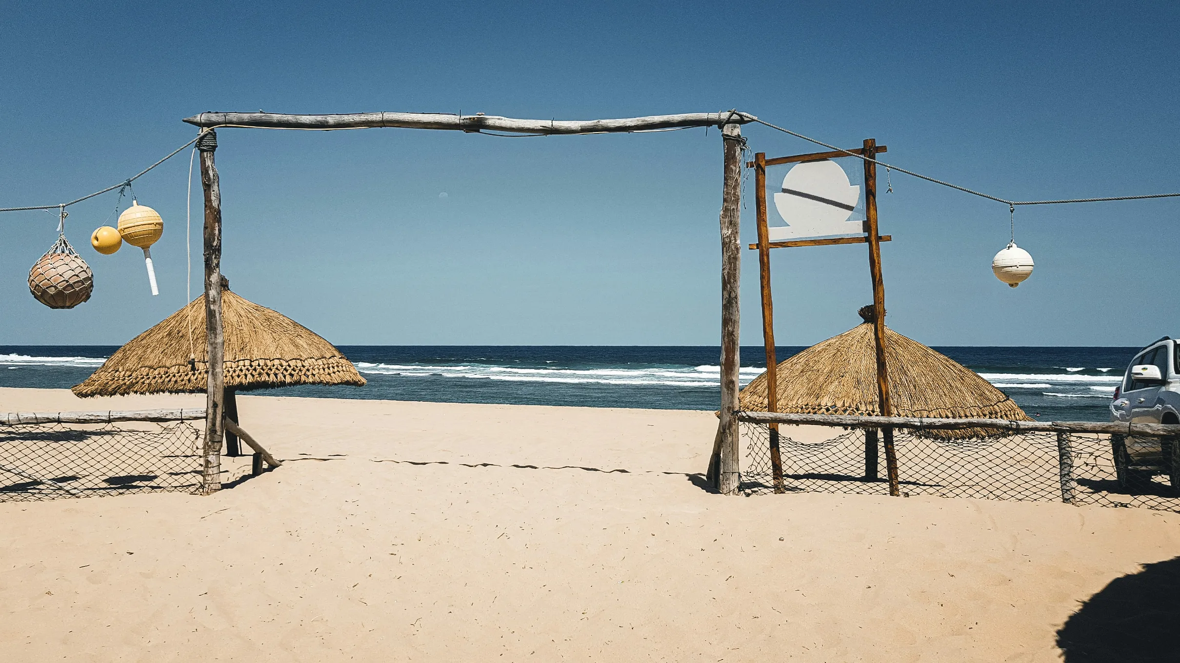 Plage paisible avec huttes en paille, bordée par une mer éclatante, idéale pour une escapade relaxante.