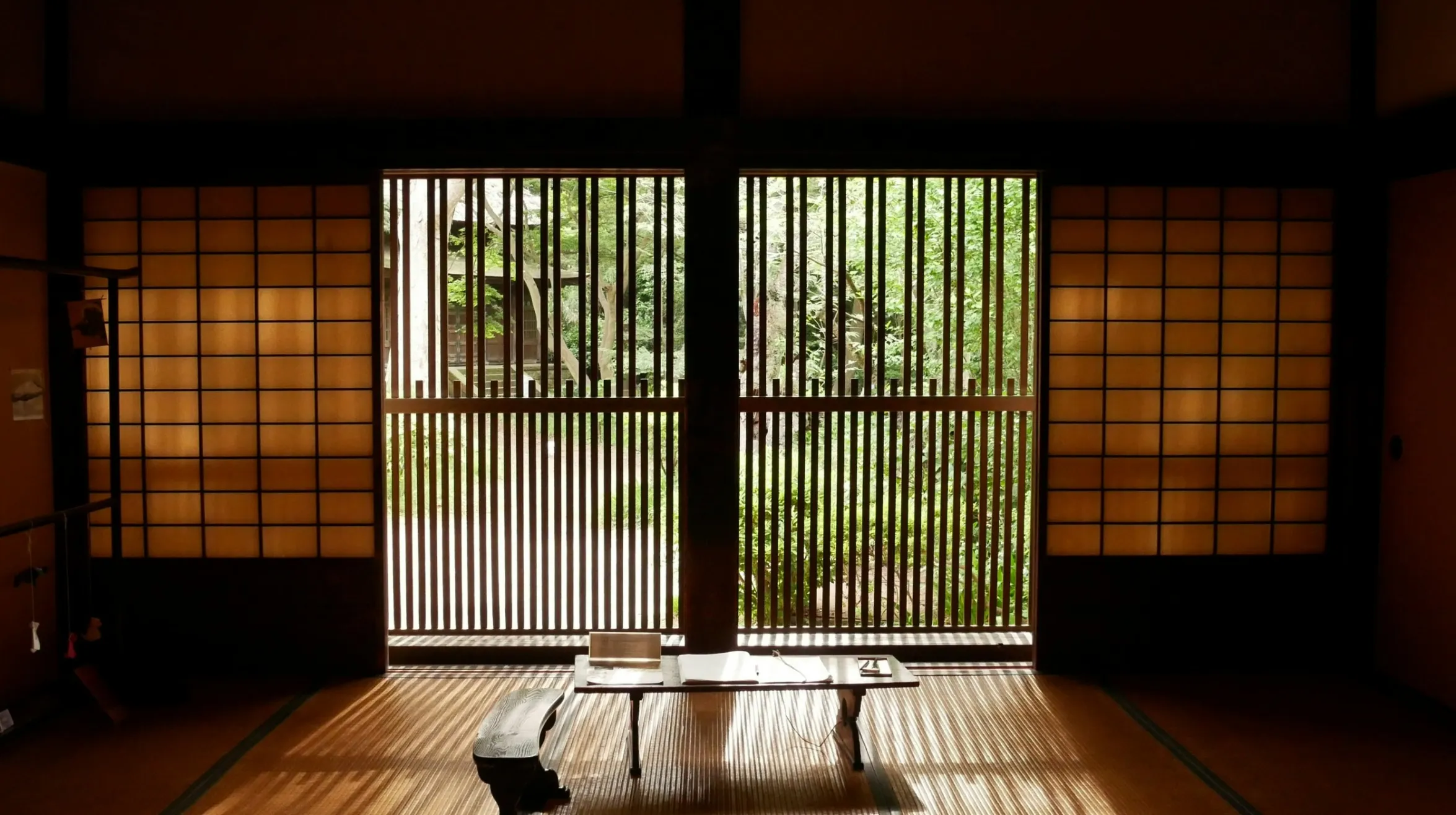 Intérieur traditionnel japonais — ambiance paisible avec vue sur un jardin luxuriant à travers des panneaux en bois.