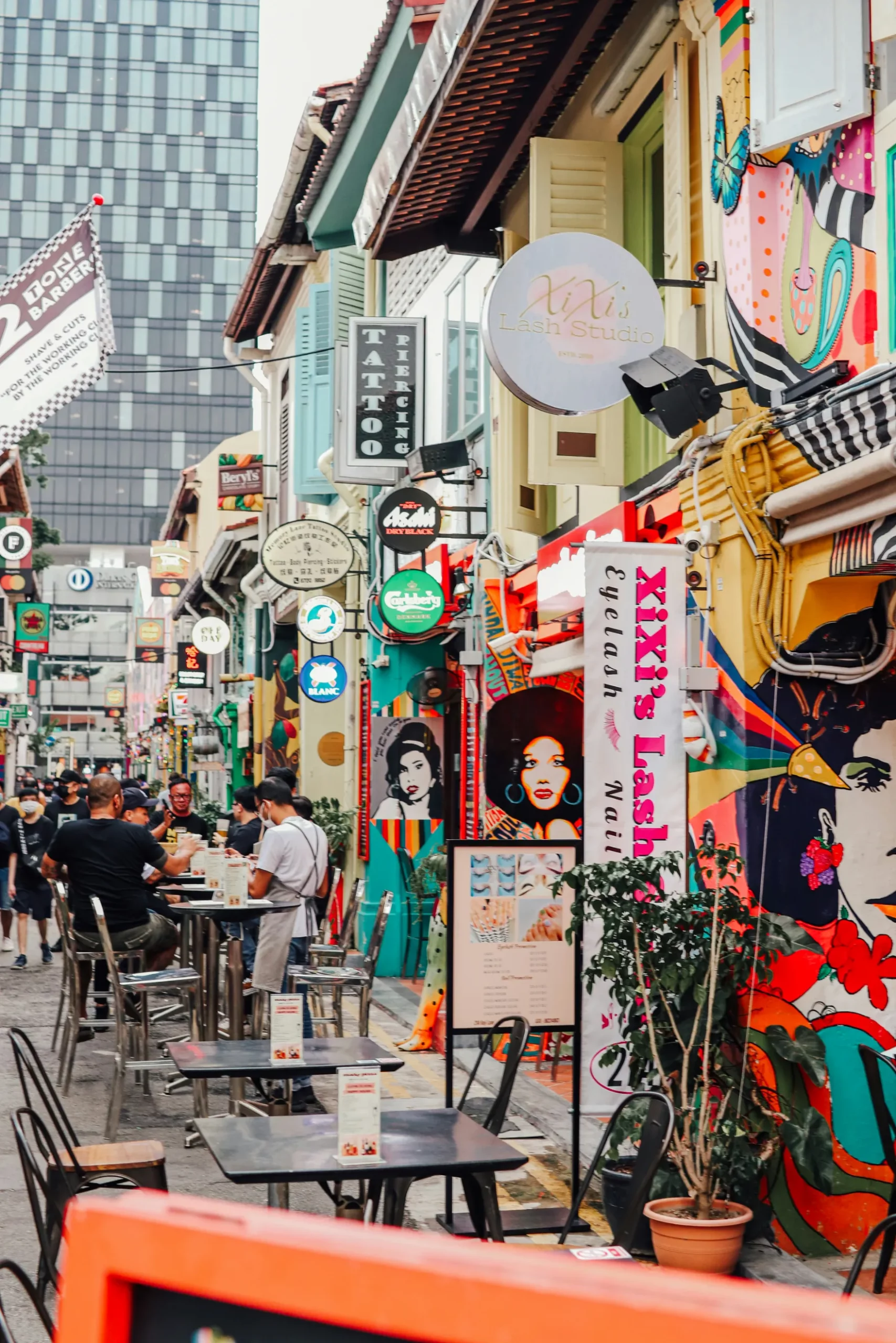 Rue animée et colorée, décorée de fresques artistiques et de cafés conviviaux, offrant une ambiance vibrante.