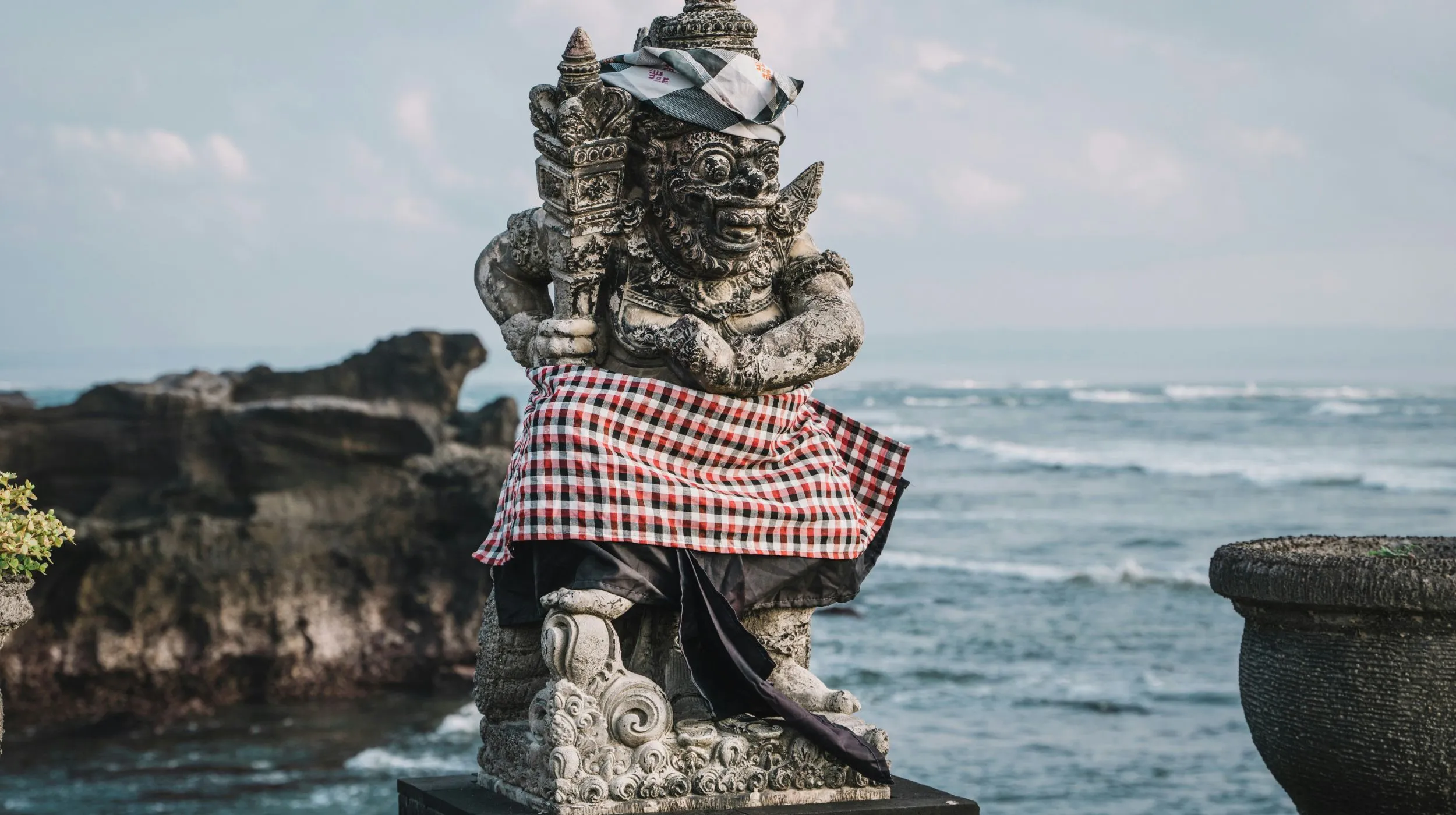 Statue majestueuse près de l'océan, entourée de rochers, offrant une vue spectaculaire sur les vagues.
