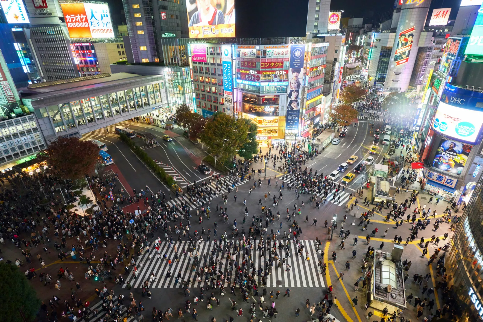 Shibuya, Japon — Une scène animée de piétons traversant un carrefour emblématique sous des lumières éclatantes.