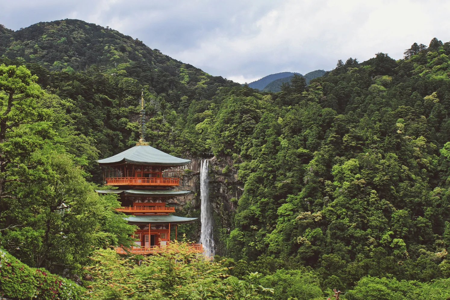 Temple majestueux entouré de verdure luxuriante et d'une cascade, Japon — un paysage enchanteur et apaisant.