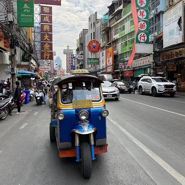 Bangkok, Thaïlande — Rue animée avec un tuk-tuk coloré et des enseignes lumineuses.