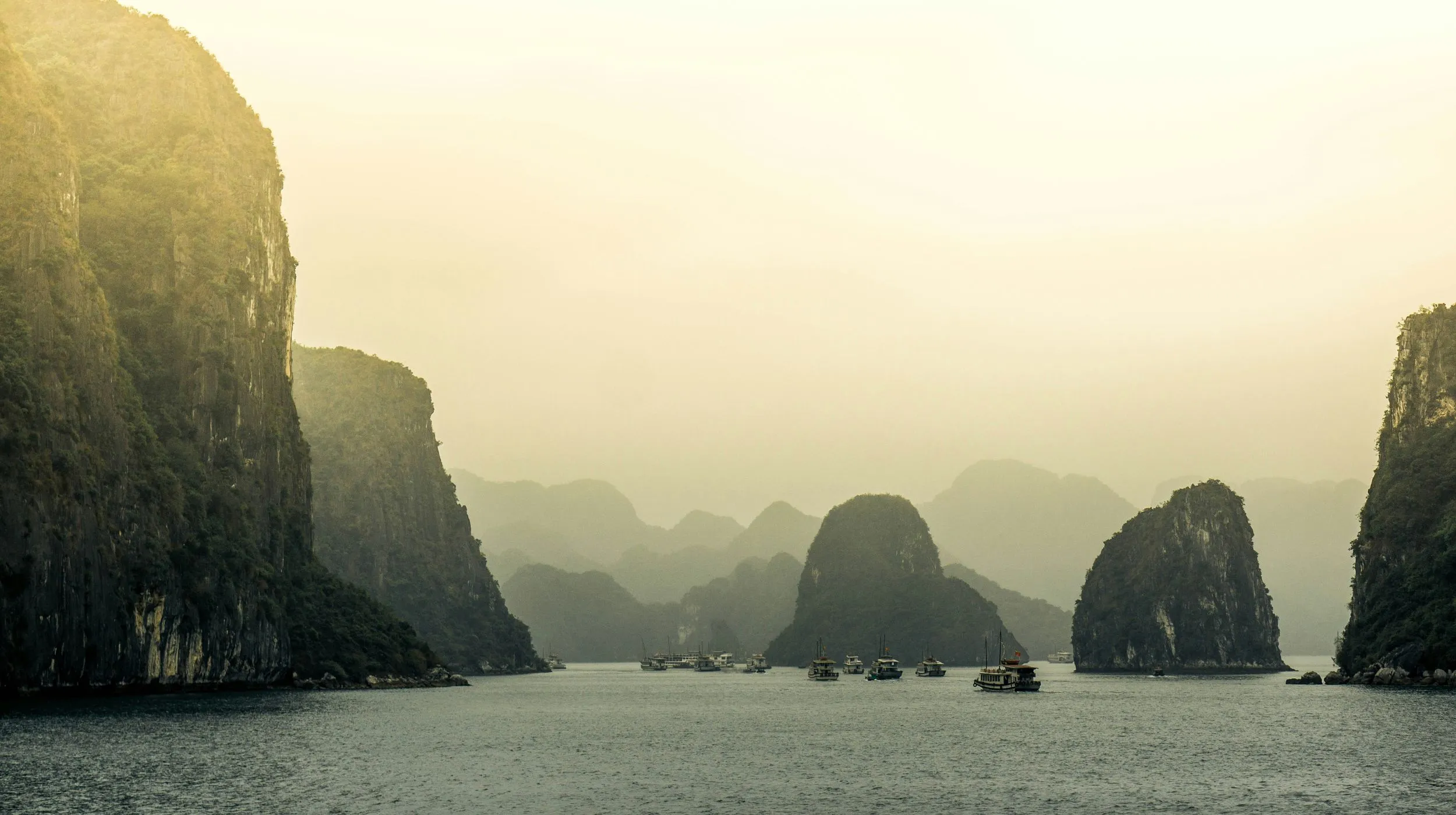 Baie d'Halong, Vietnam — paysages spectaculaires de formations rocheuses émergeant d'une mer calme et brumeuse.
