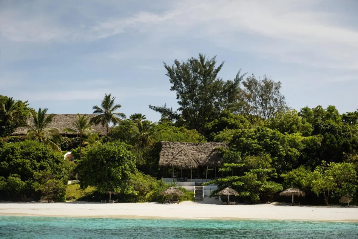 Plage paisible avec des huttes en bord de mer, entourée d'une végétation luxuriante.