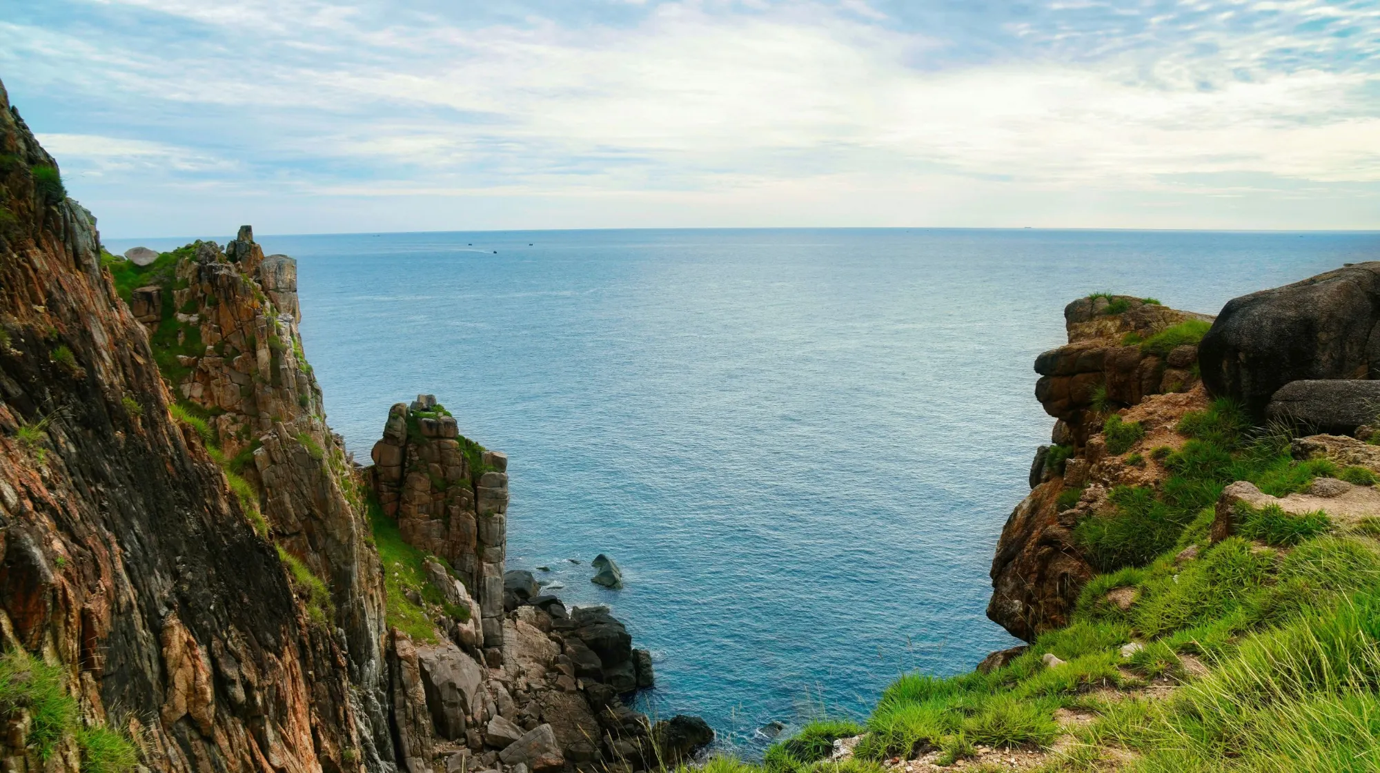 Côte sauvage et paisible surplombant un océan calme, entourée de falaises majestueuses.